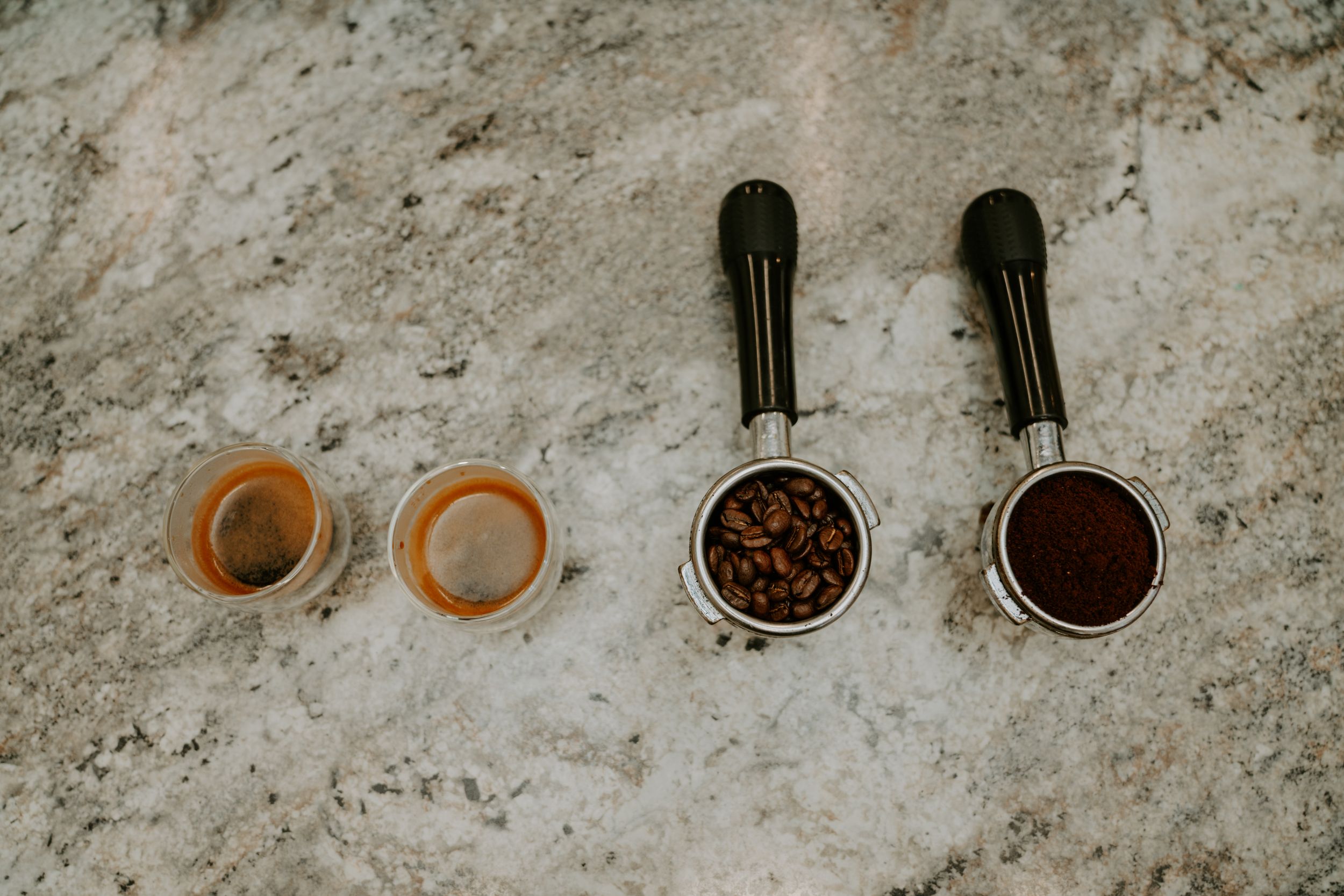 Coffee brewing equipment and ingredients laid out on a textured concrete surface.
