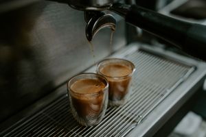 Double shot espresso being pulled into glass cups on a commercial coffee machine.