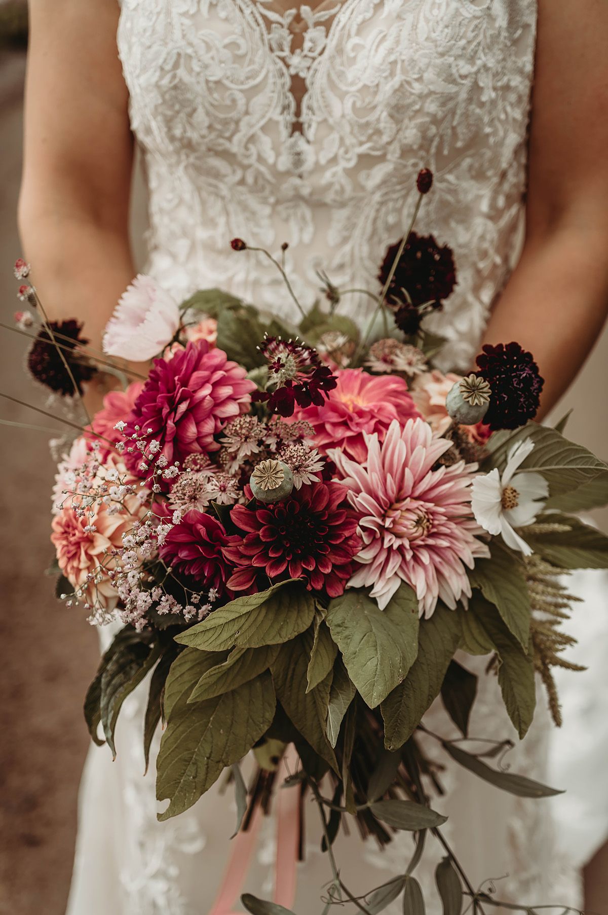 Bröllopsbukett med rosa och röda blommor, dahlia och rosenskära, arrangerad i rund spretig form. Foto av bröllopsfotograf Lets Bloom Media.