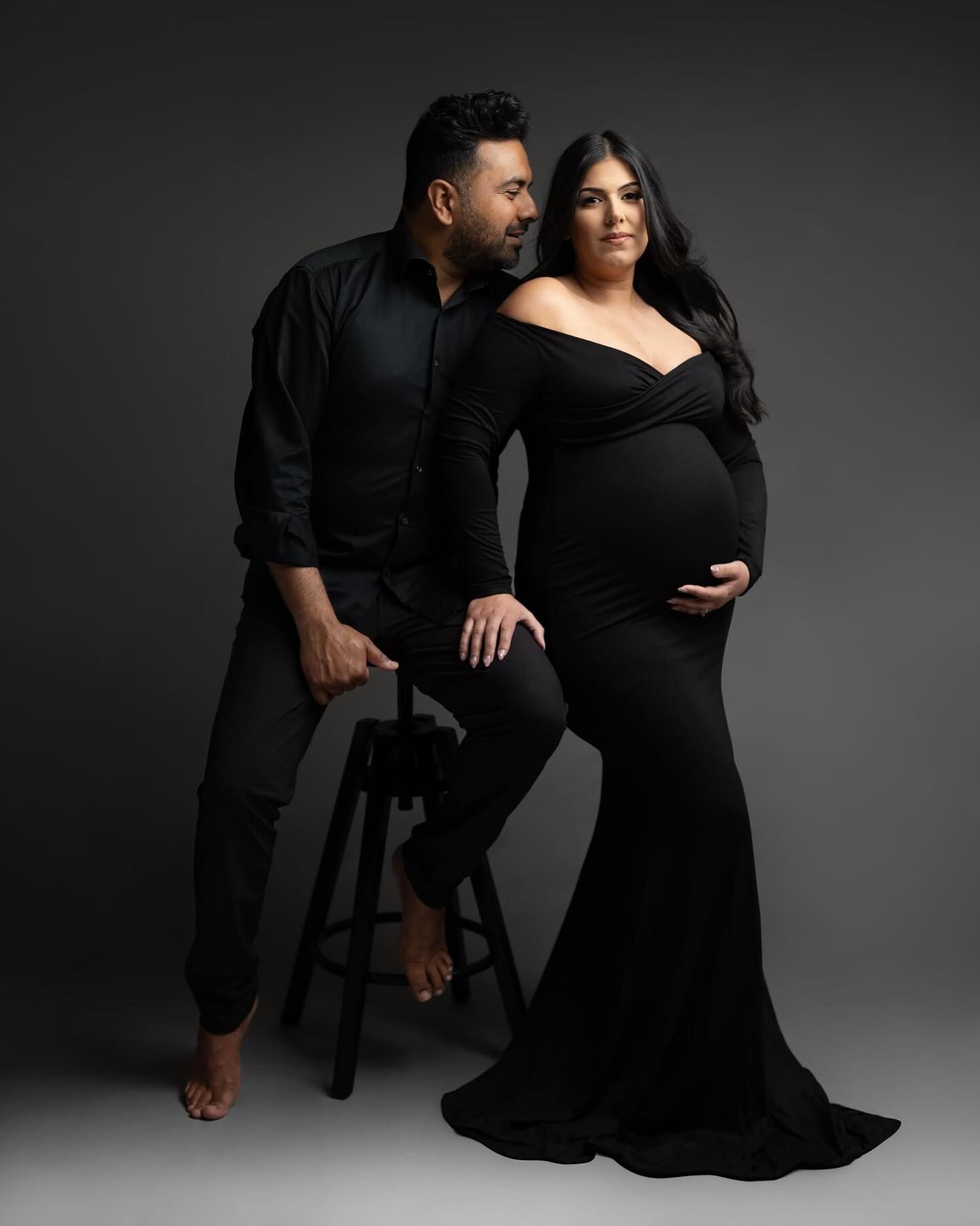 A romantic couple in black attire poses intimately against a dark gray studio backdrop in a series of artistic shots.