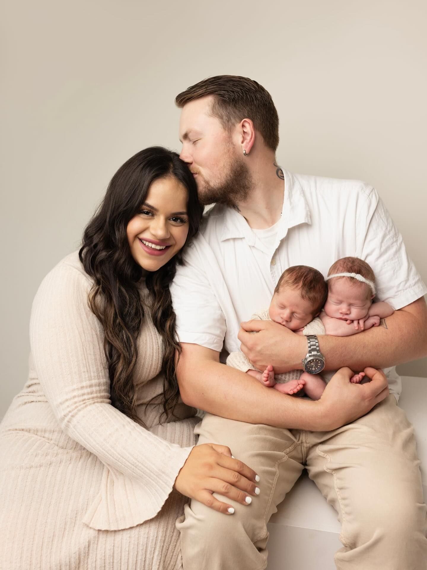 A family portrait series in neutral tones showing tender moments with newborn twins in a minimalist studio setting.
