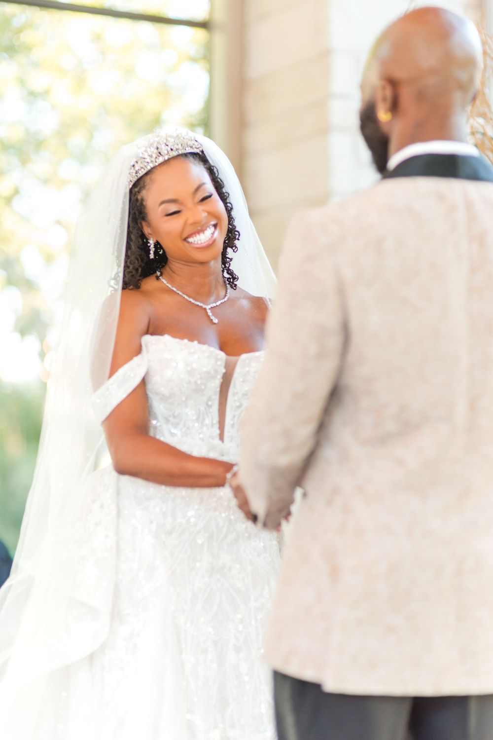 A happy couple shares a joyful moment on their wedding day, with the bride wearing an elegant white lace gown.