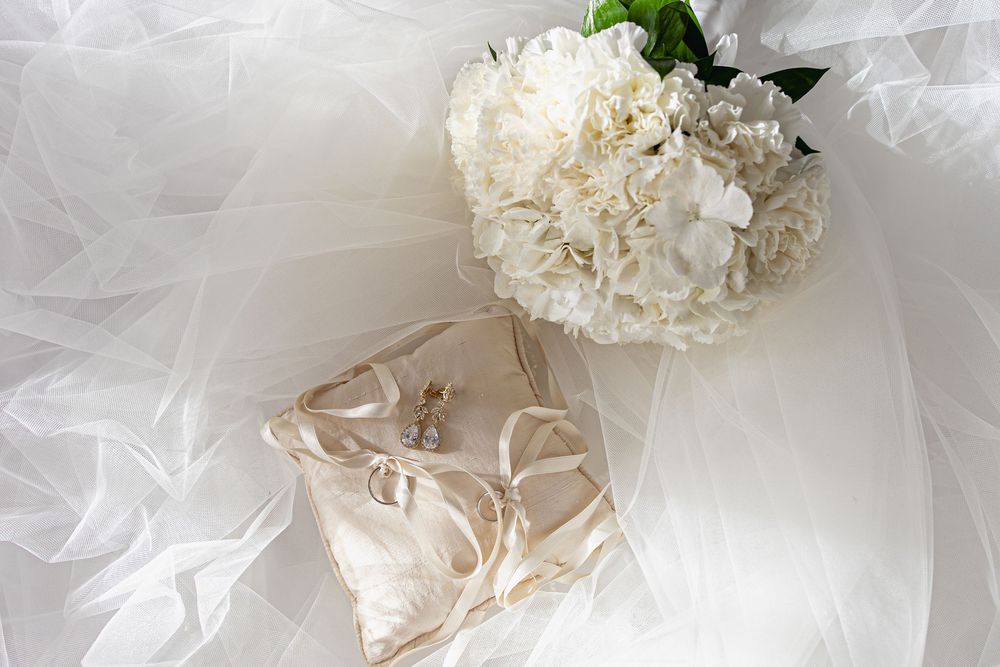 Delicate white tulle fabric and lace wedding accessories arranged on a light background.