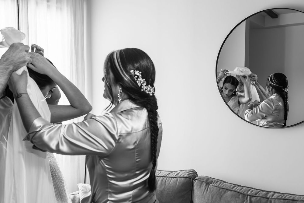 A sequence of black and white photos showing someone putting on a dress and adjusting their hair in a mirror.