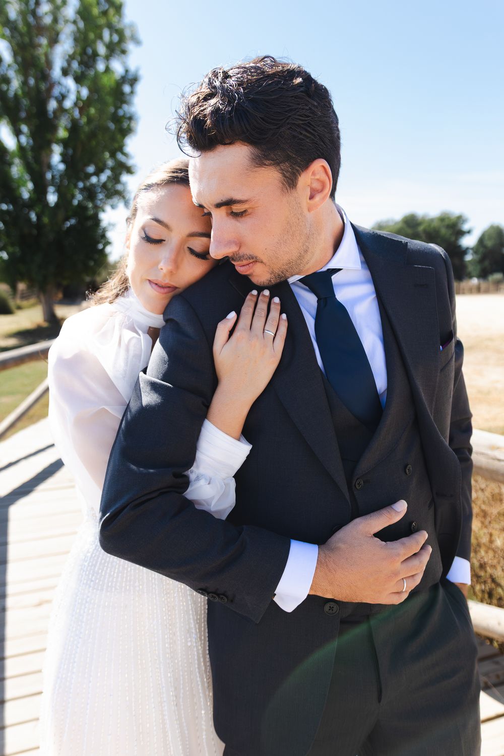 A romantic moment between newlyweds embracing outdoors in formal wedding attire.