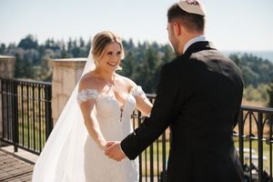 A bride and groom share intimate moments on a scenic balcony overlooking a forest landscape during their wedding day.