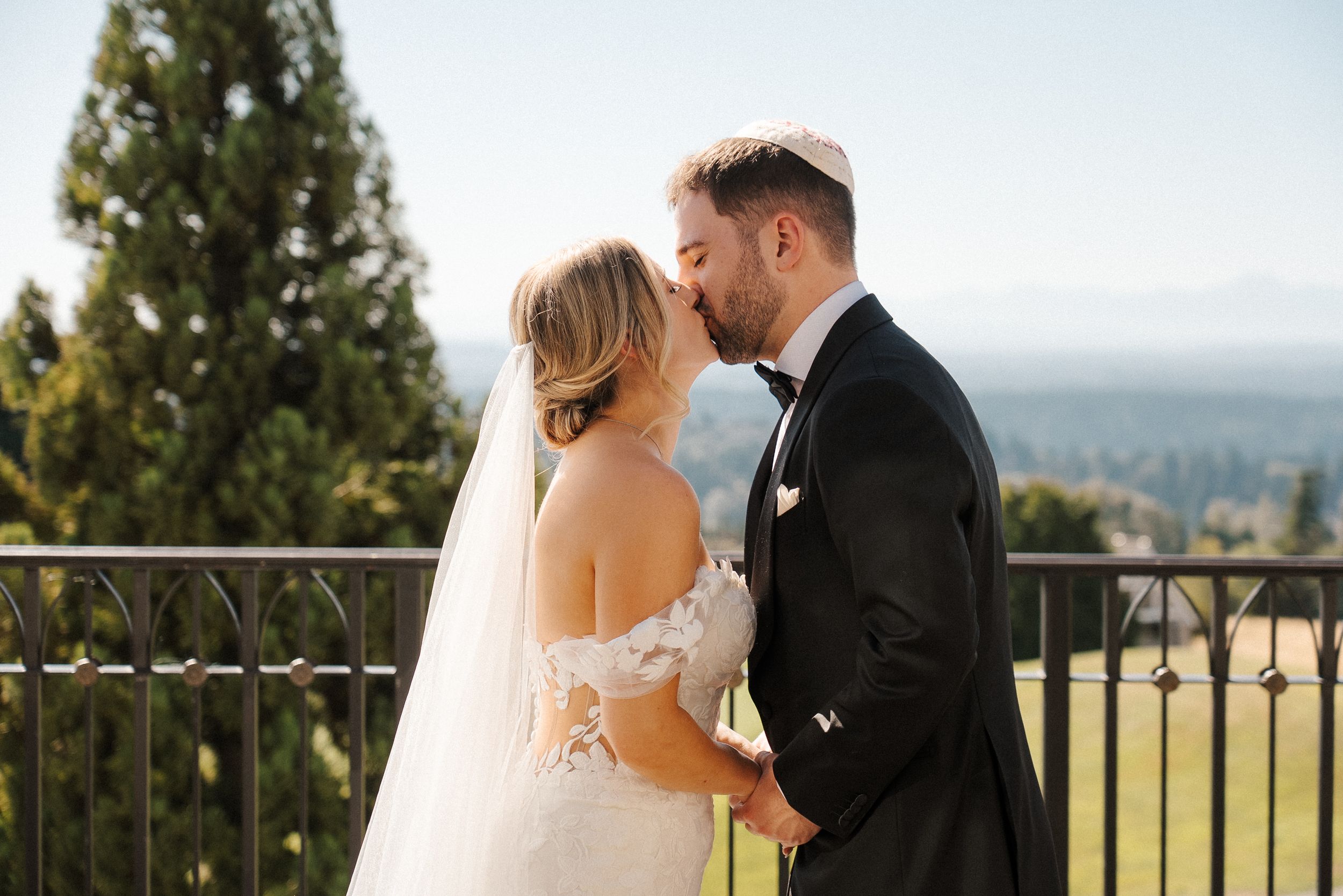 A couple shares a romantic moment on their wedding day overlooking a scenic mountain landscape.