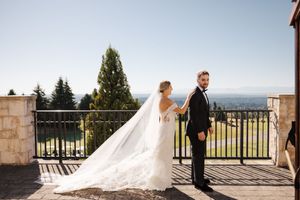 Wedding couple embraces on elegant stone terrace with sweeping mountain vista in background.