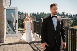 Elegant wedding couple stands on stone balcony overlooking scenic mountain landscape on their special day.