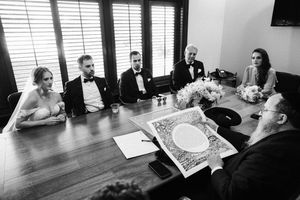 Black and white photograph showing people seated at a conference table during a business meeting.
