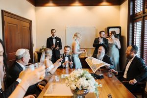 A panoramic view of a wedding reception room with guests mingling and socializing around elegant tables and decor.