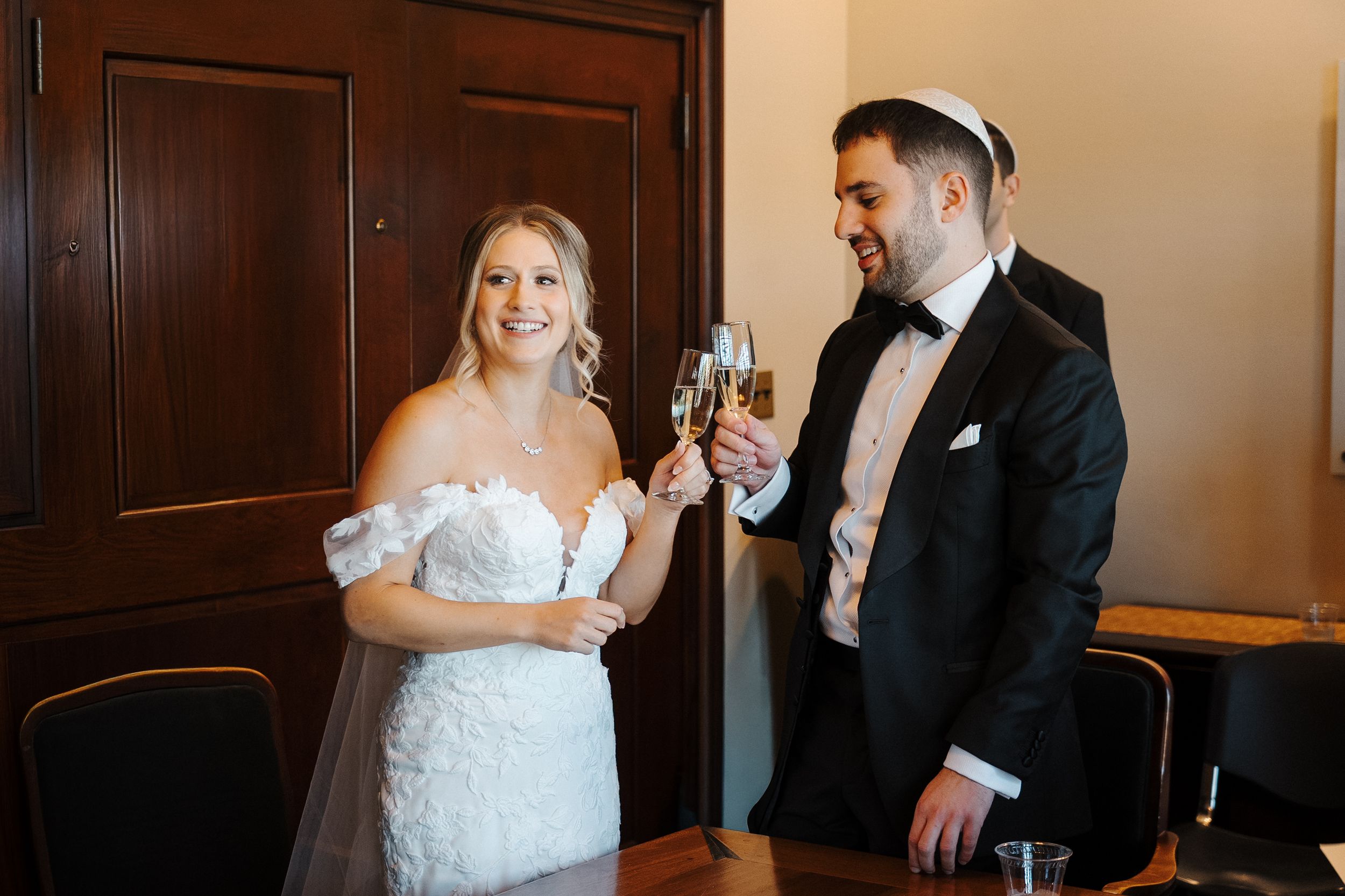 A bride and groom share a candid moment during their wedding celebration in an elegant indoor setting.