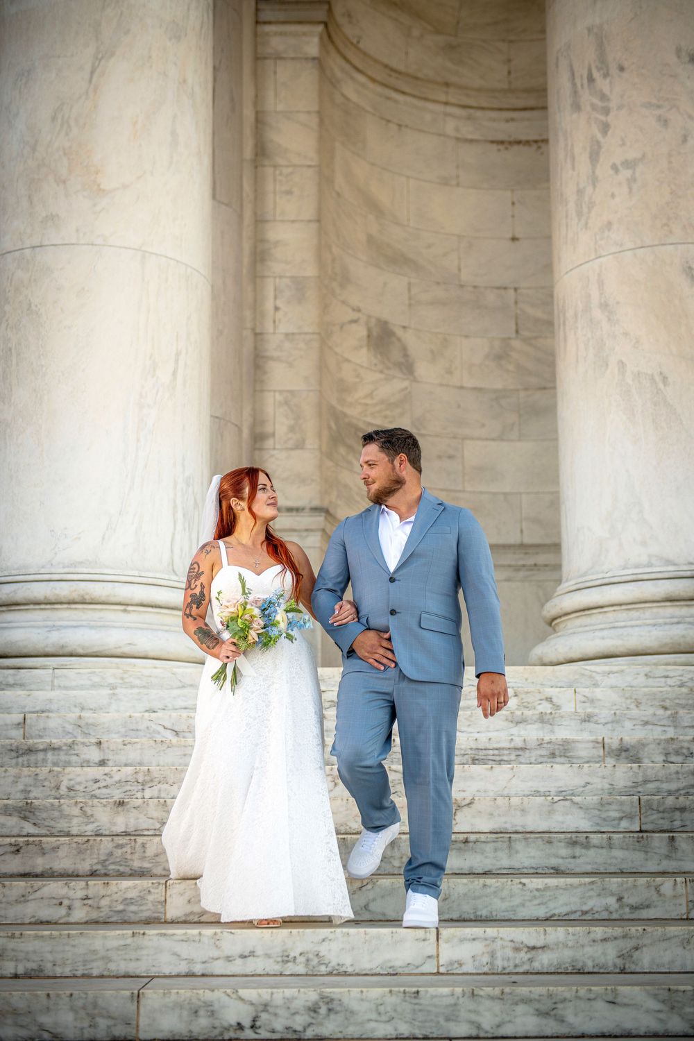 A couple in wedding attire share romantic moments against a backdrop of elegant stone columns.
