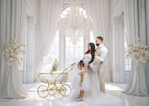 Family maternity portrait in white ornate room with vintage gold baby carriage.