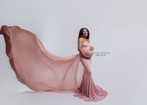 Maternity photo of woman in flowing pink dress with fabric billowing behind her.