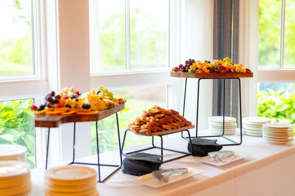 A bright modern dining room buffet setup with various dishes displayed on raised platforms near sunlit windows.