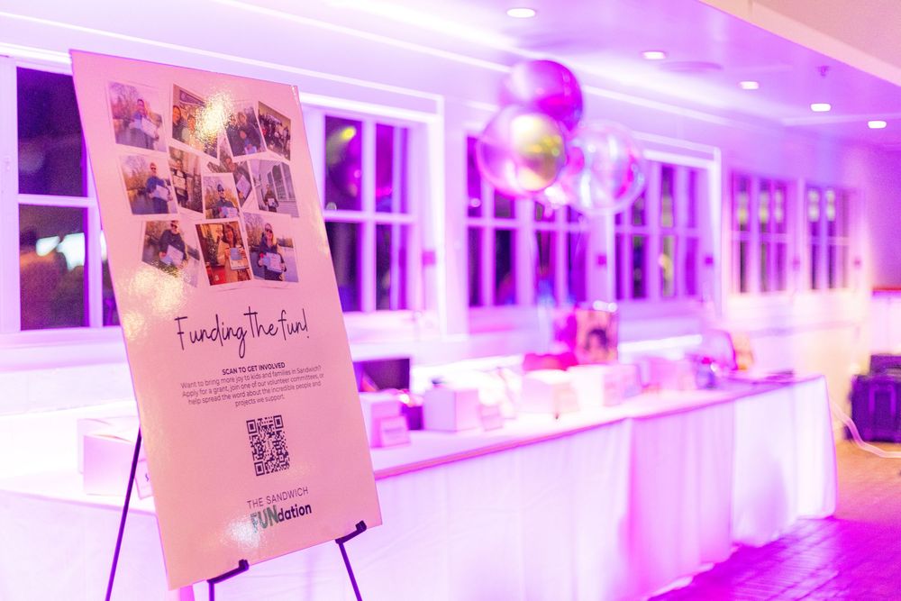 Modern event space illuminated in vibrant purple lighting with white decor and display stands.