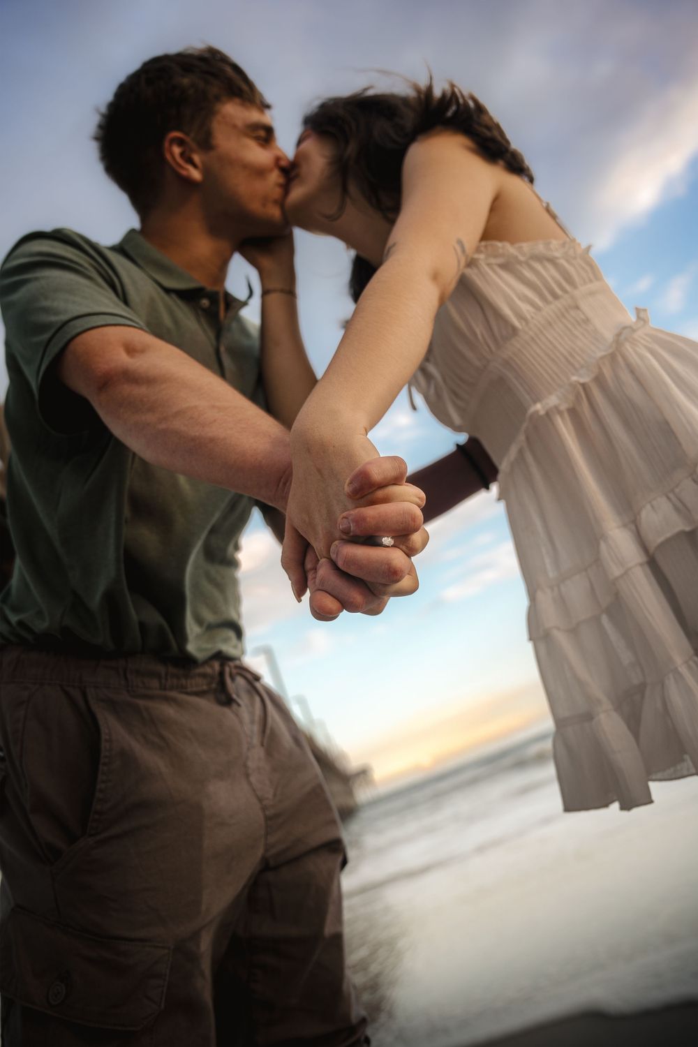 A couple in silhouette against a cloudy sky hold hands and dance in a series of connected romantic poses.