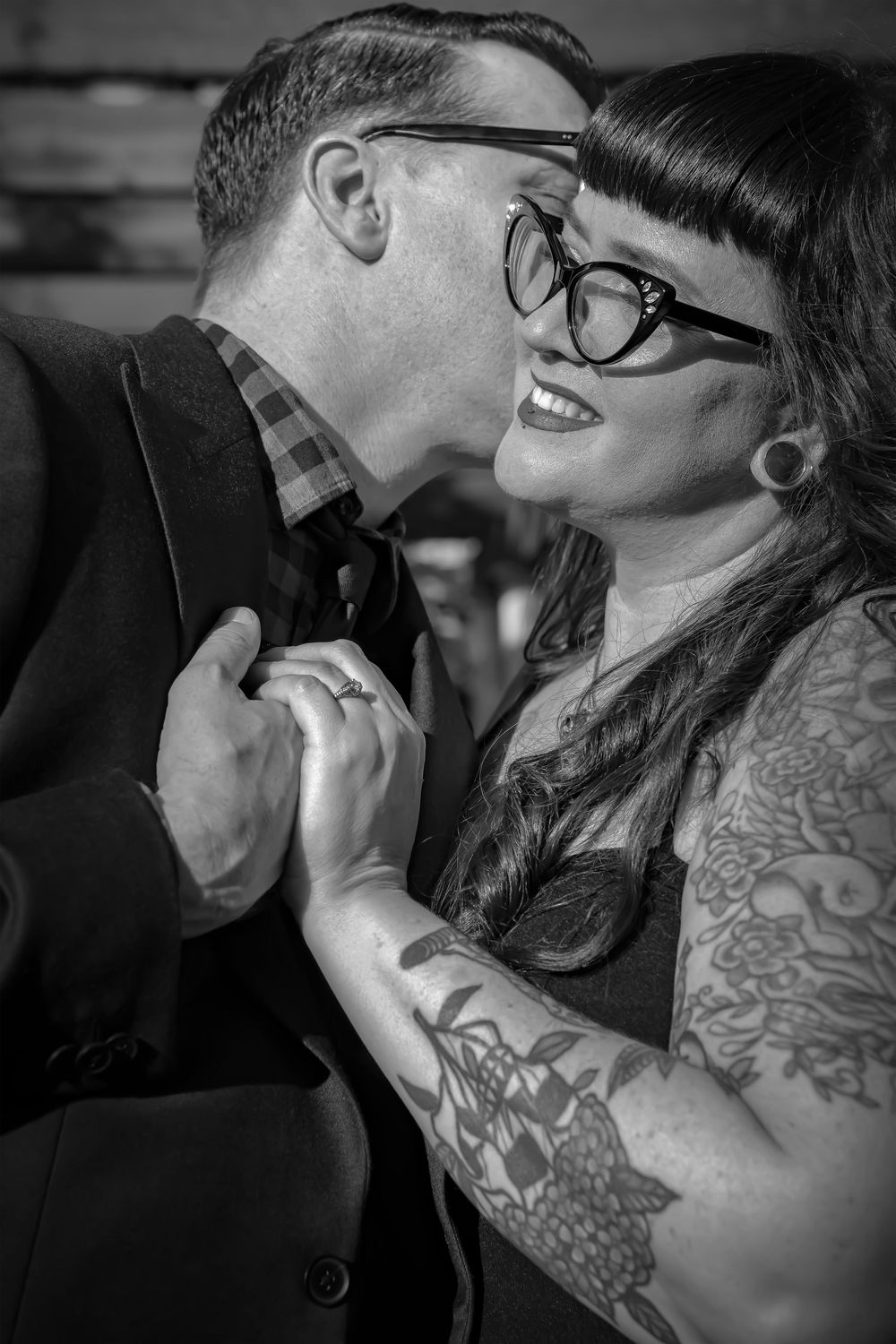 Black and white photo series showing an intimate kiss between two people, one with visible tattoo sleeves.