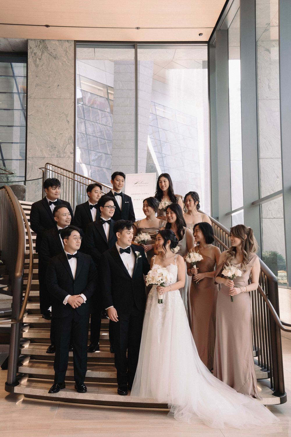 Wedding party poses elegantly in a modern venue with white and neutral tones.