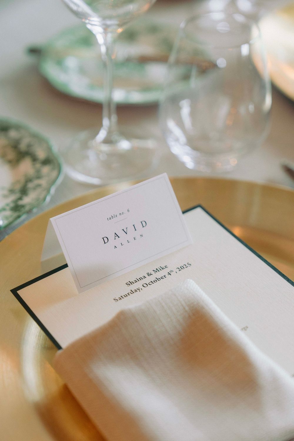 Close-up of a formal place setting with name card and wine glasses on elegant table.