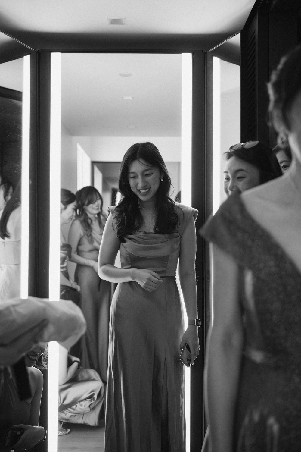 A group of wedding guests getting ready in an elegantly lit hallway.