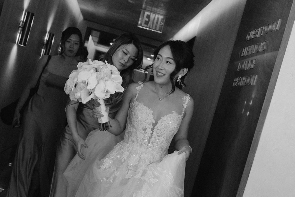 Wedding party members walking down a hallway with exit signs visible.