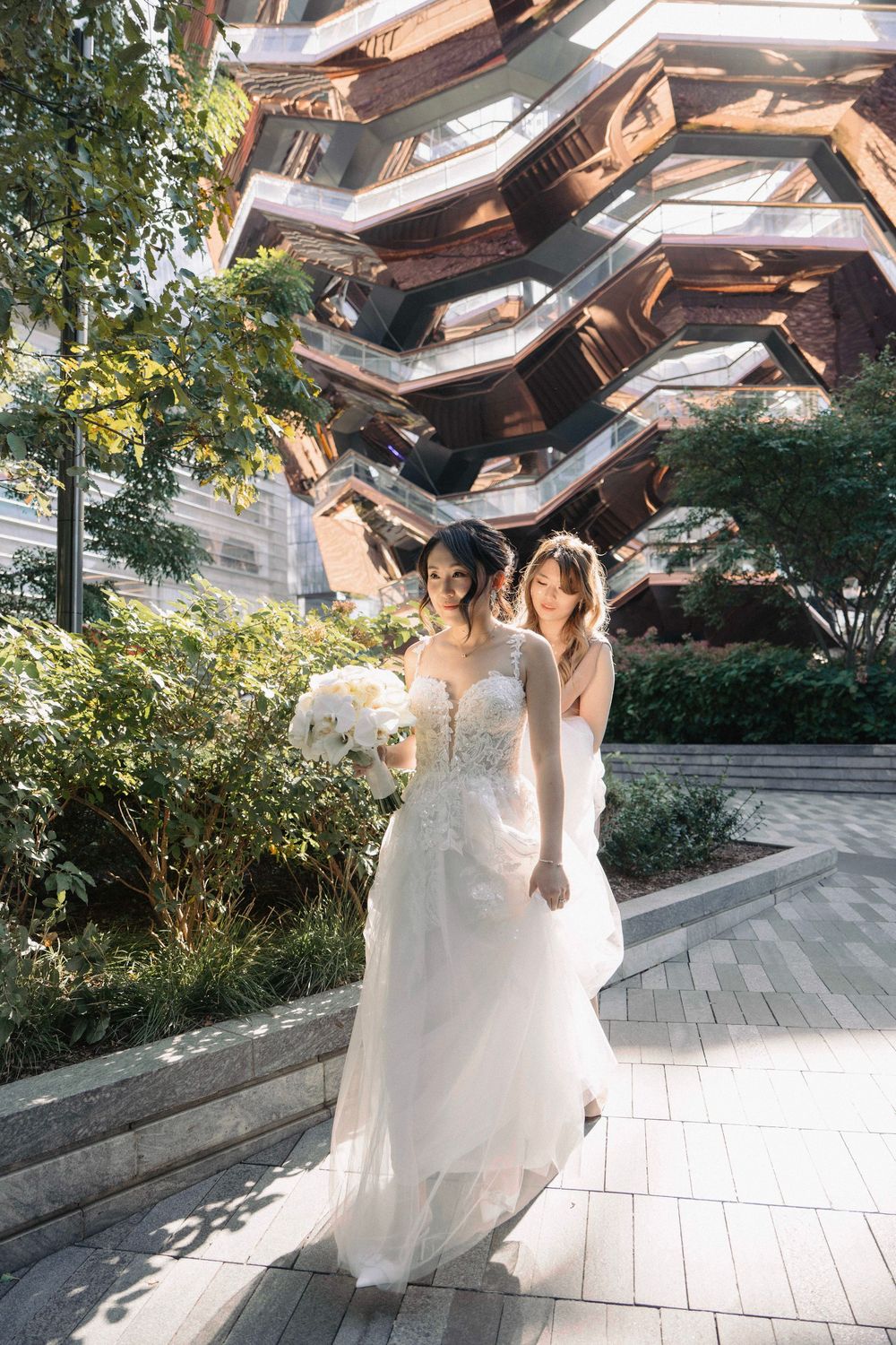 Person in a flowing white wedding gown twirling in an outdoor plaza with modern architecture.