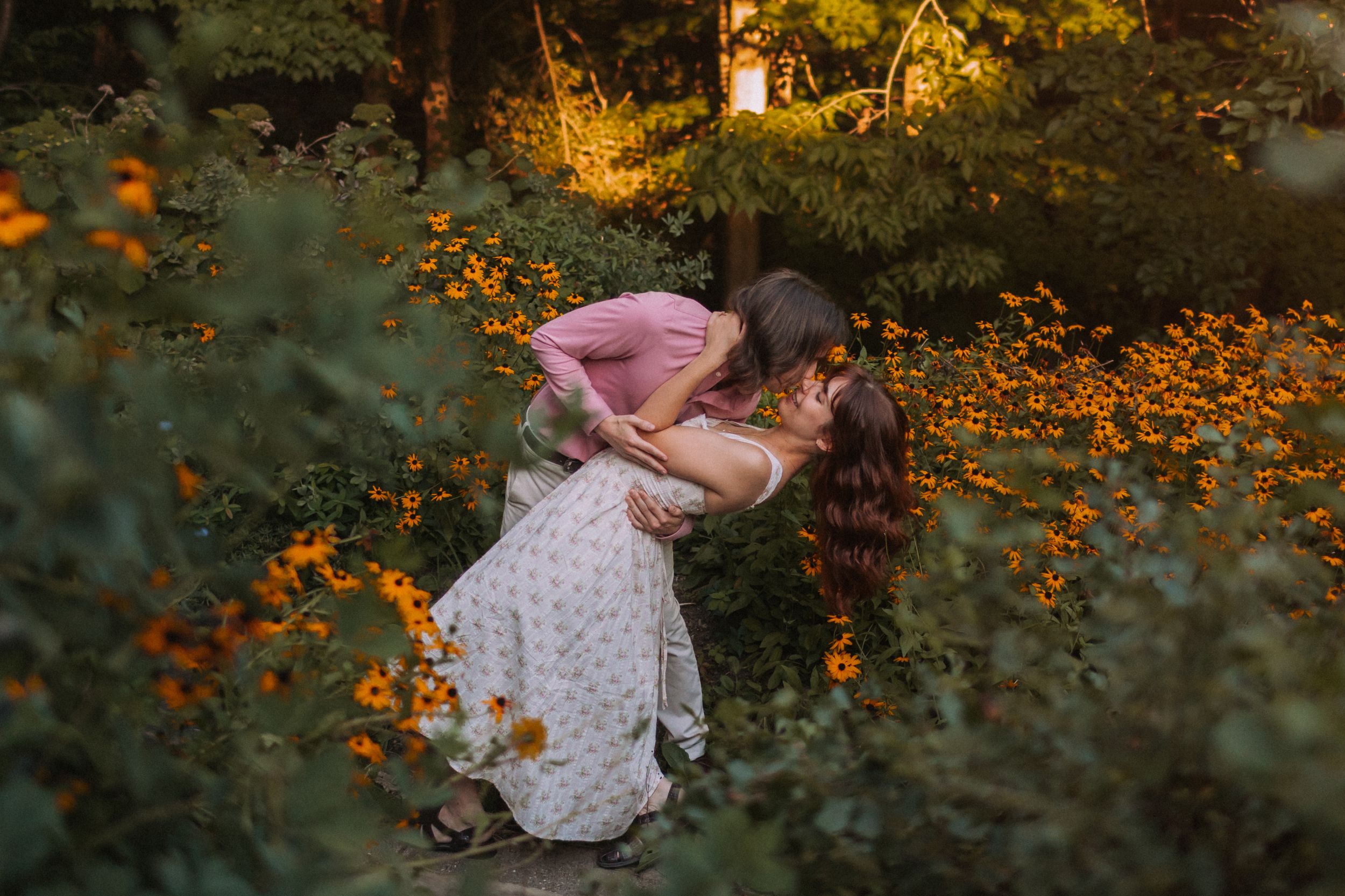 Couple embracing among orange flowers during outdoor photo session.
