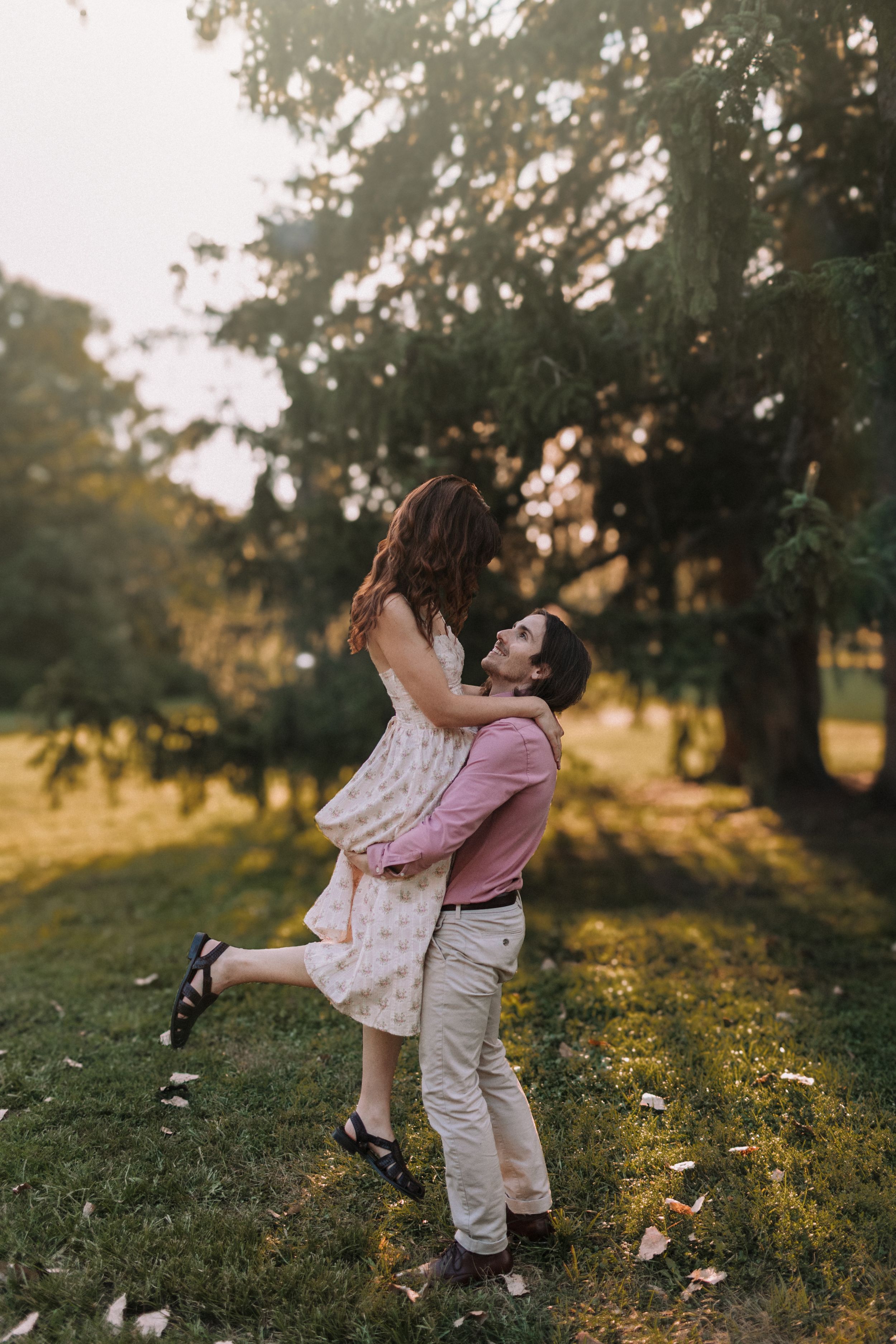 A romantic lift pose in a sunlit garden with golden evening light.