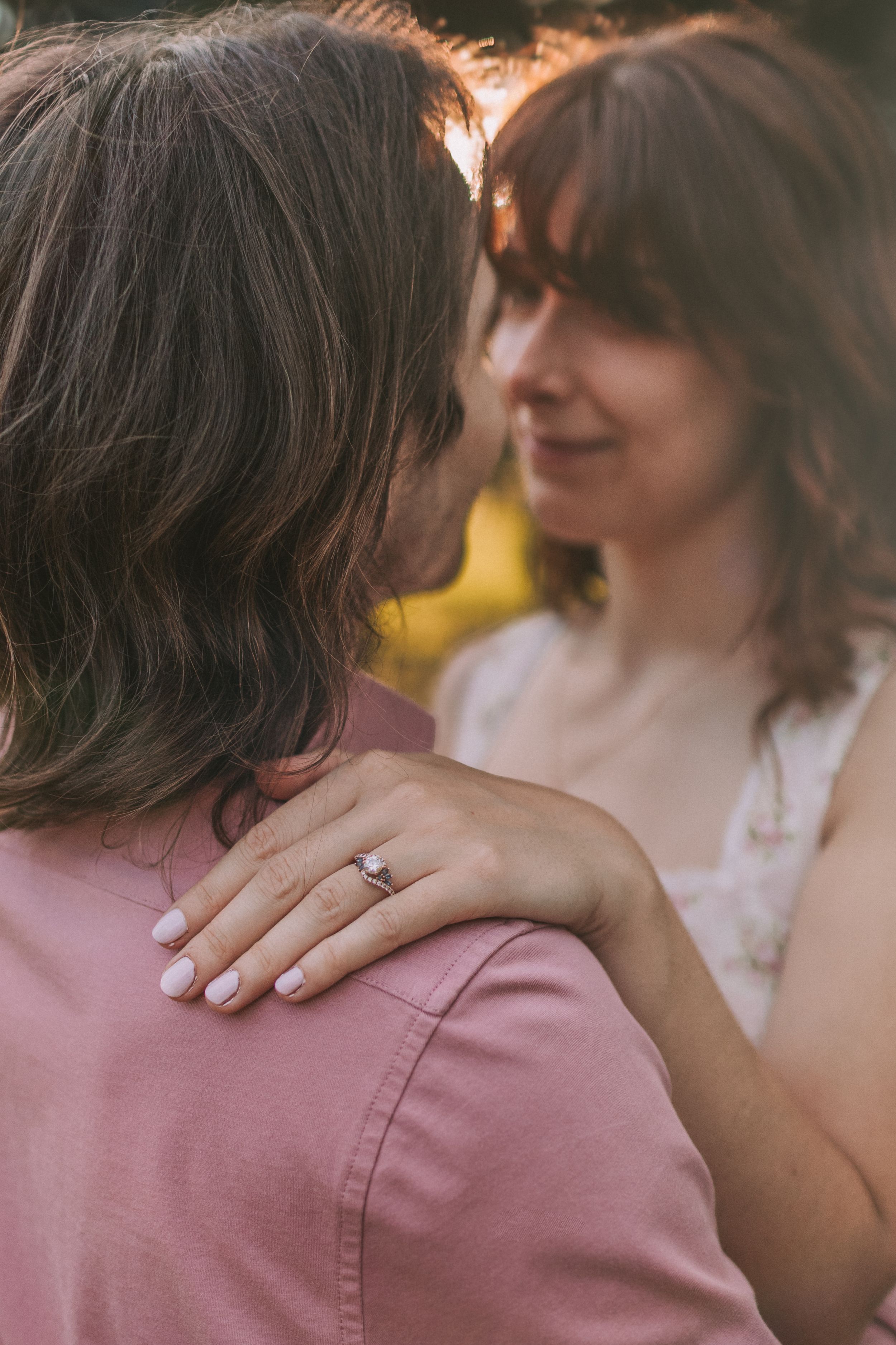 Close-up series of a romantic moment between a couple wearing pink and white, with an engagement ring visible.