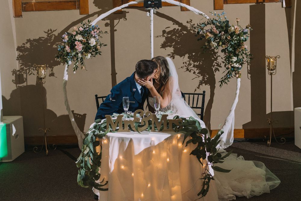 Wedding ceremony space with white floral arch and twinkling lights.