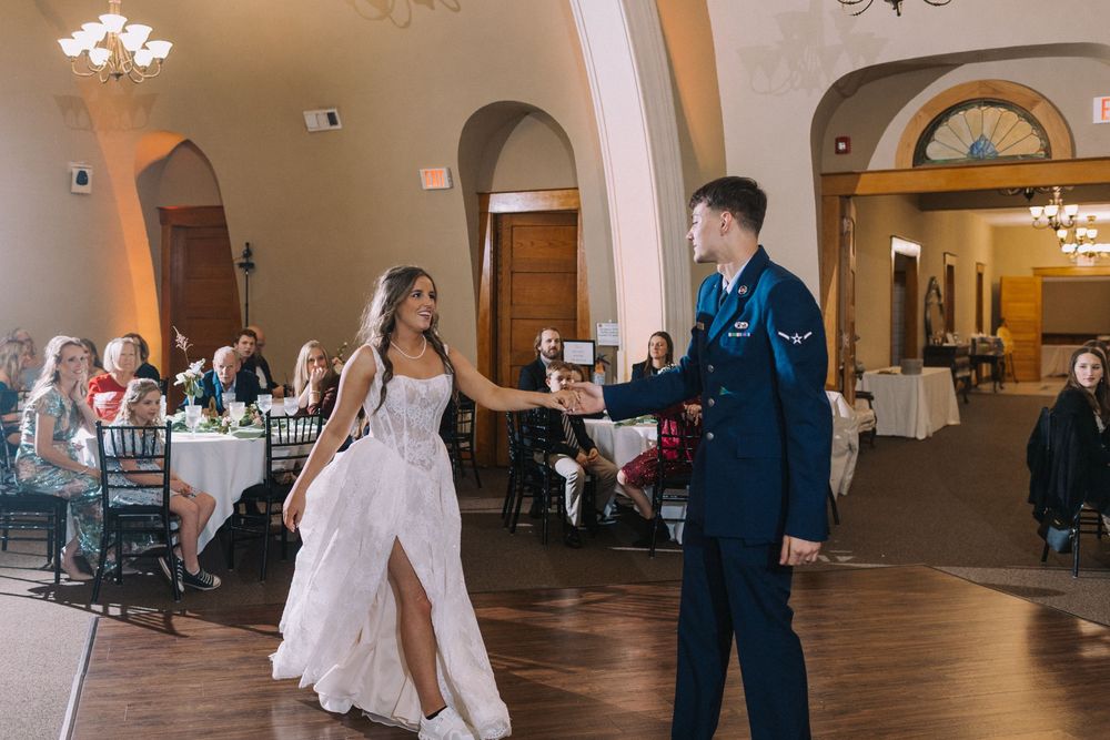 Wedding reception ballroom with arched windows and elegant chandeliers.