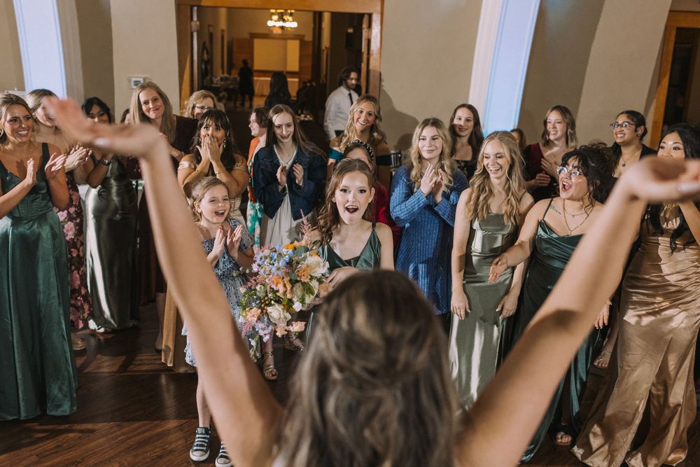 Wedding reception crowd raises their hands in celebration during a dance party.