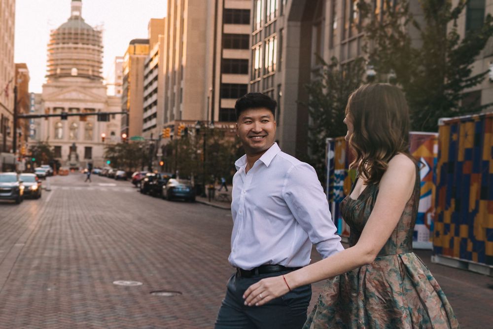 Couple walking on urban street with historic domed building in background.