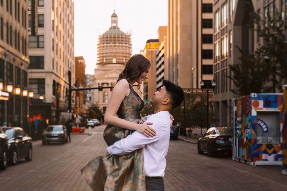 Couple sharing a romantic moment on a cobblestone street in downtown with historic buildings in the background.