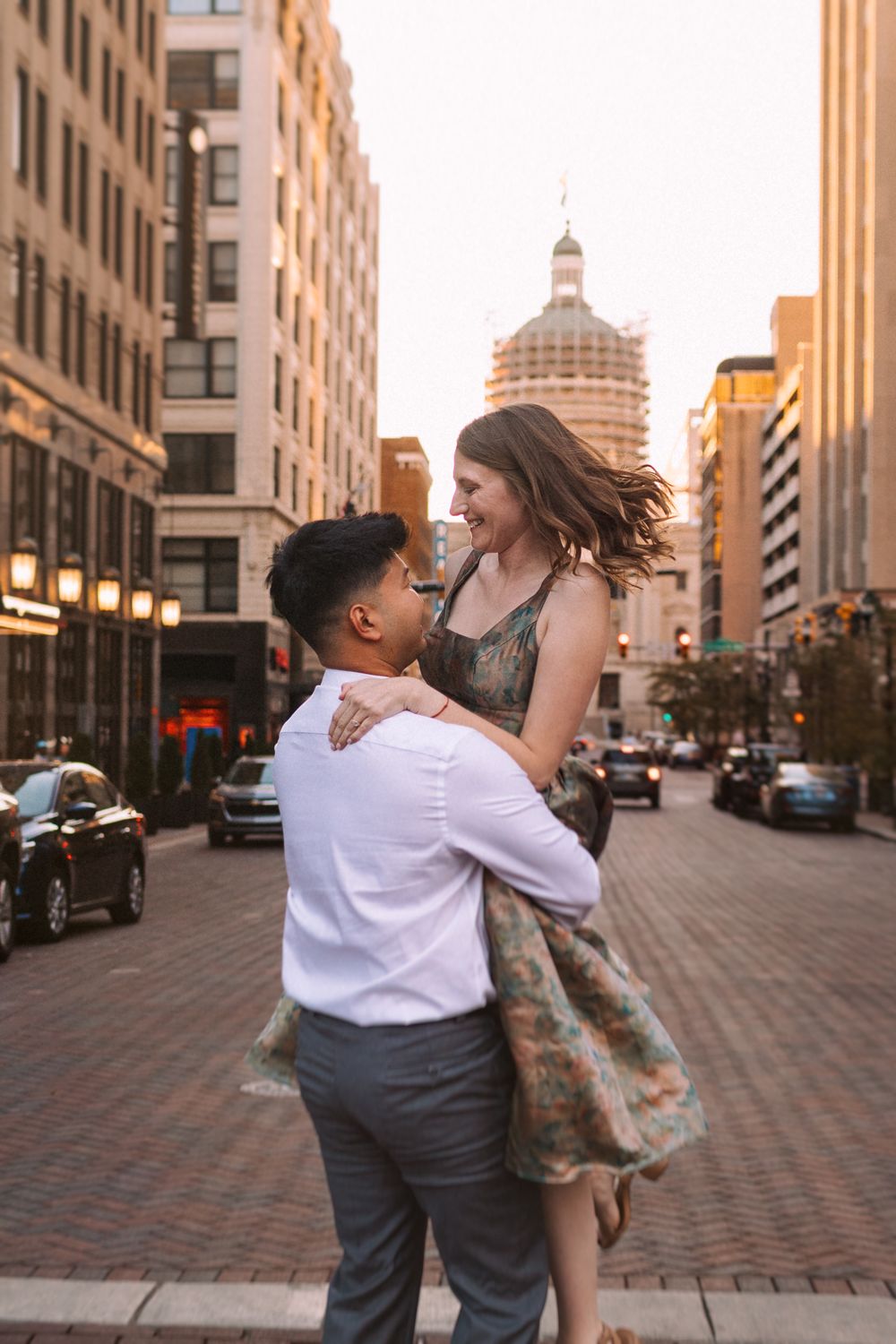 Romantic couple dancing on city street with historic architecture in background.