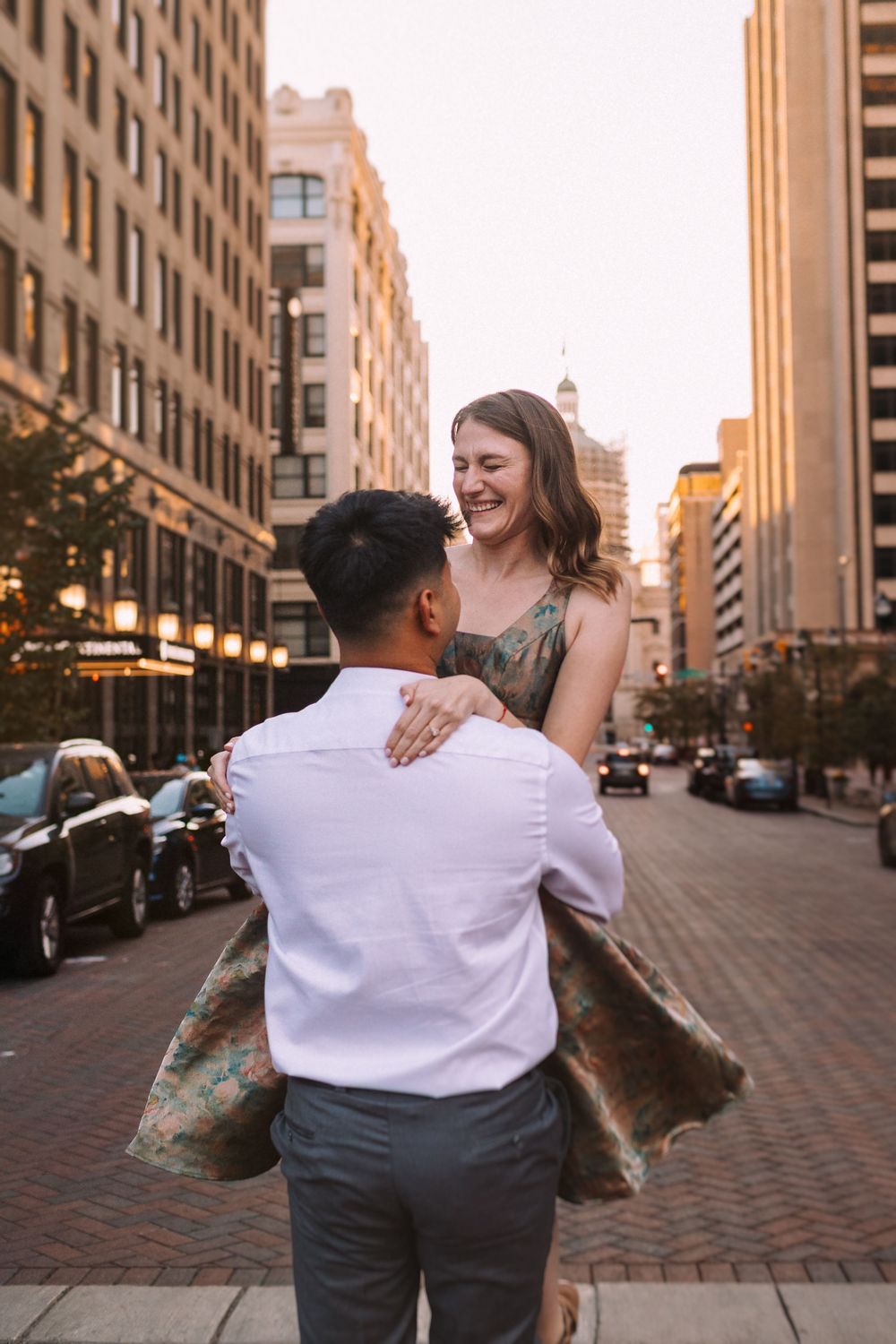Couple embracing and laughing together on an urban street during golden hour.