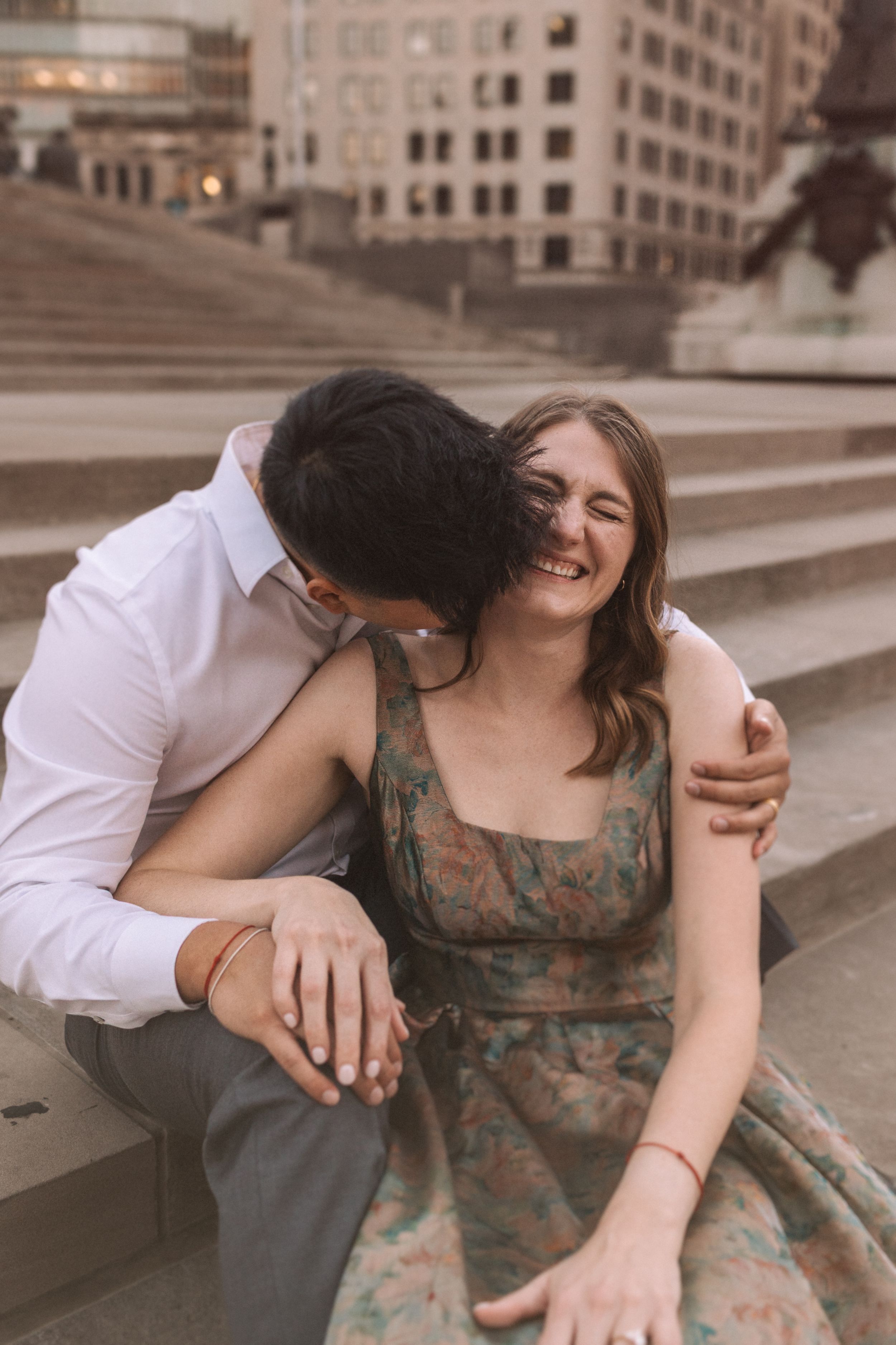 A couple shares playful moments on concrete steps in a romantic photoshoot sequence.