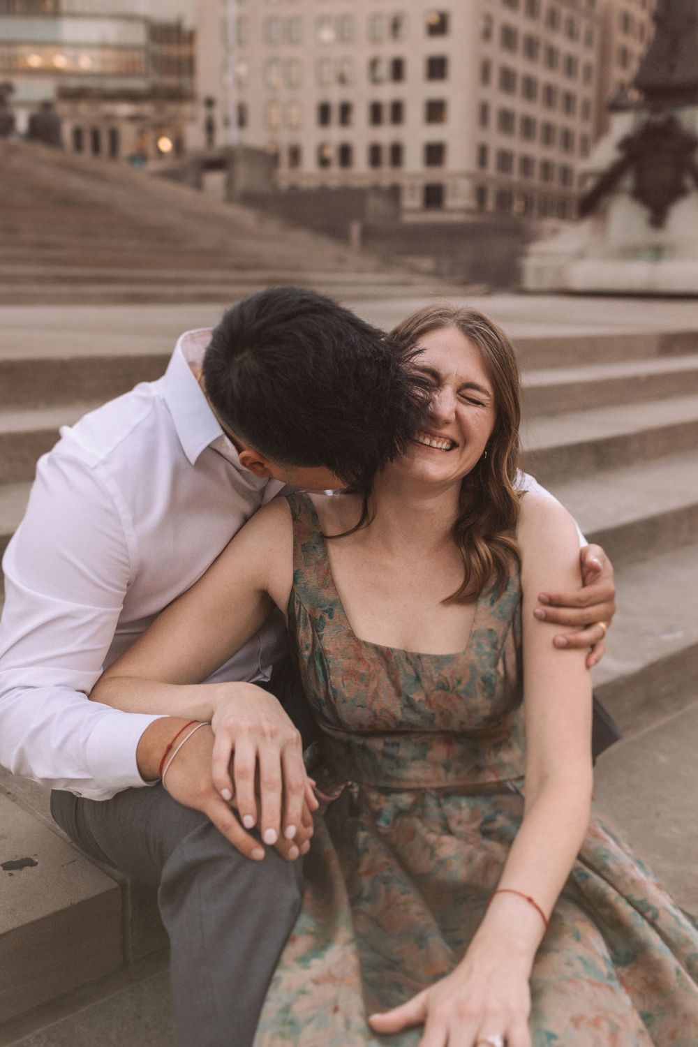 A couple shares playful moments on concrete steps in a romantic photoshoot sequence.
