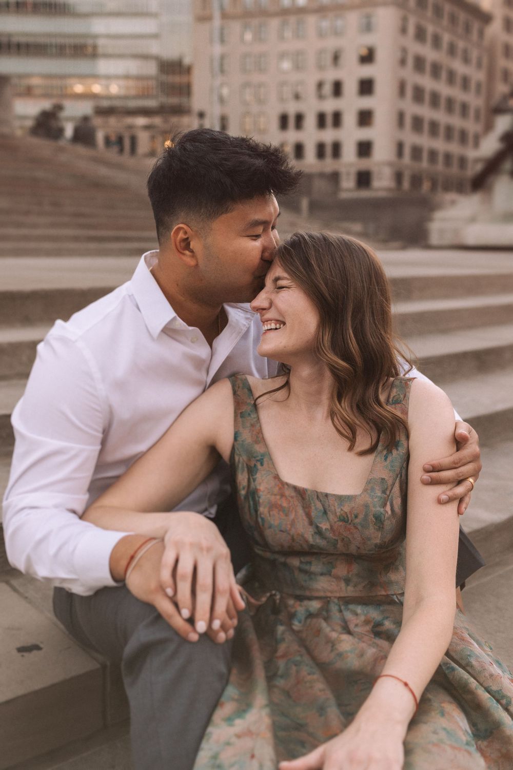 Sweet candid moments between couple sitting on stone steps in urban setting.