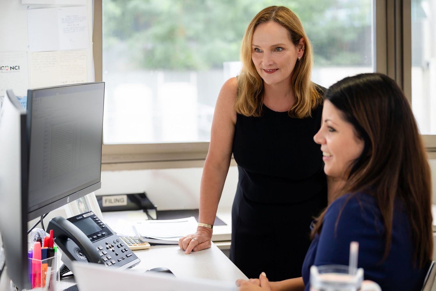 Business professionals gather around a conference table for a meeting in a modern office setting.