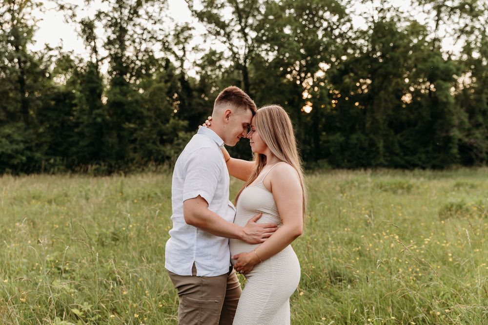 A couple shares a romantic moment in a sunlit meadow during a sunset photo session.