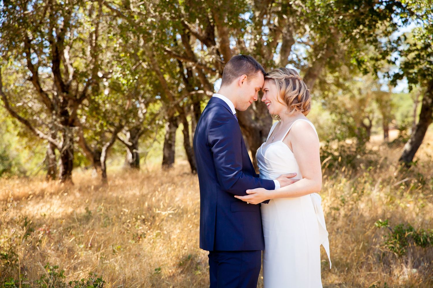 A romantic wedding couple embraces while wearing a white dress and navy suit in an intimate outdoor portrait series.