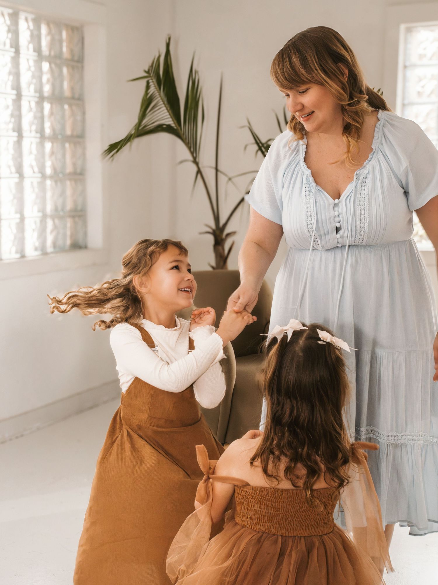 Mother and daughter share joyful moments in a bright, airy room with plants.