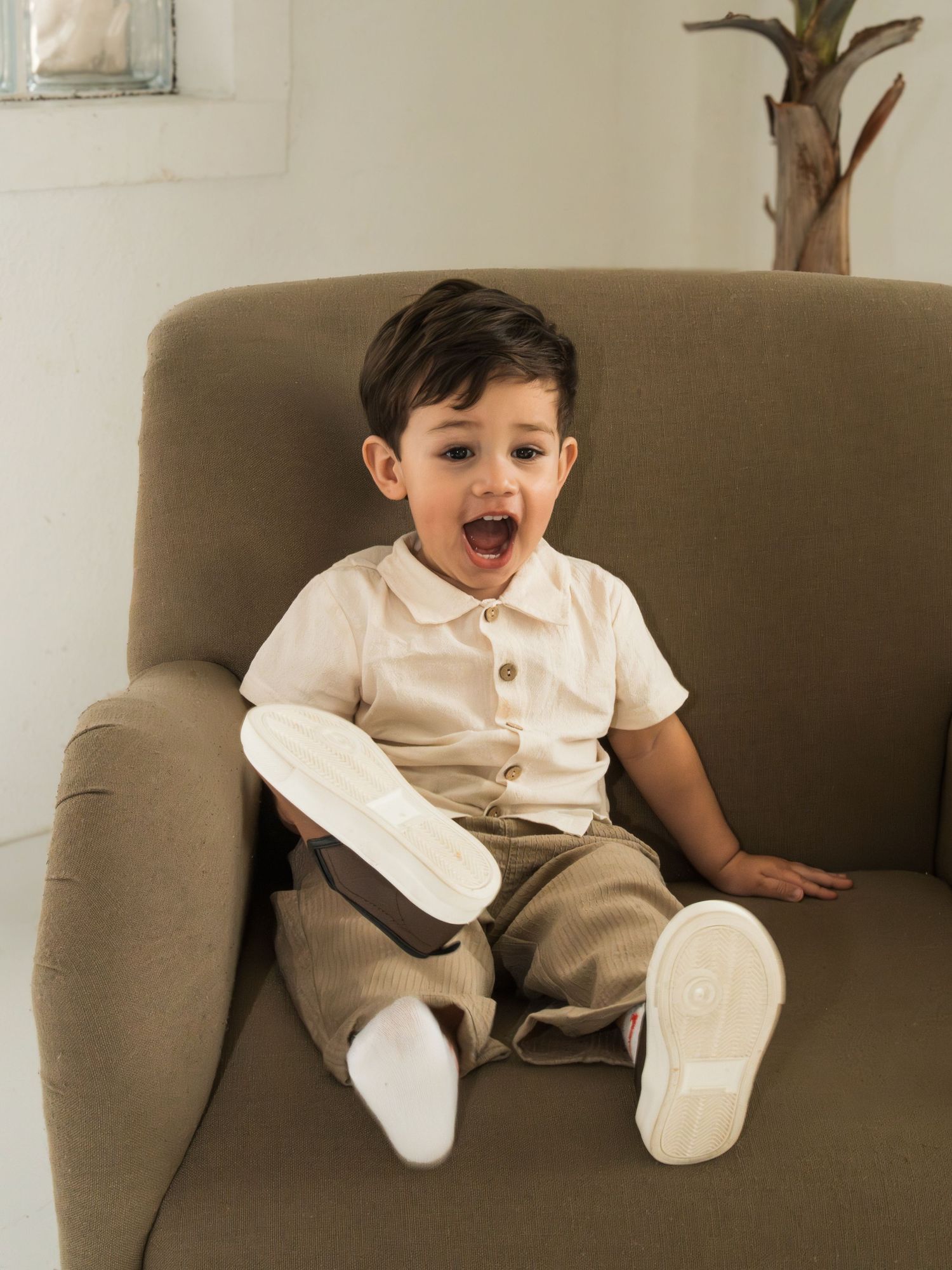 A series of photos showing a small child sitting on a beige couch wearing a white shirt and khaki pants.