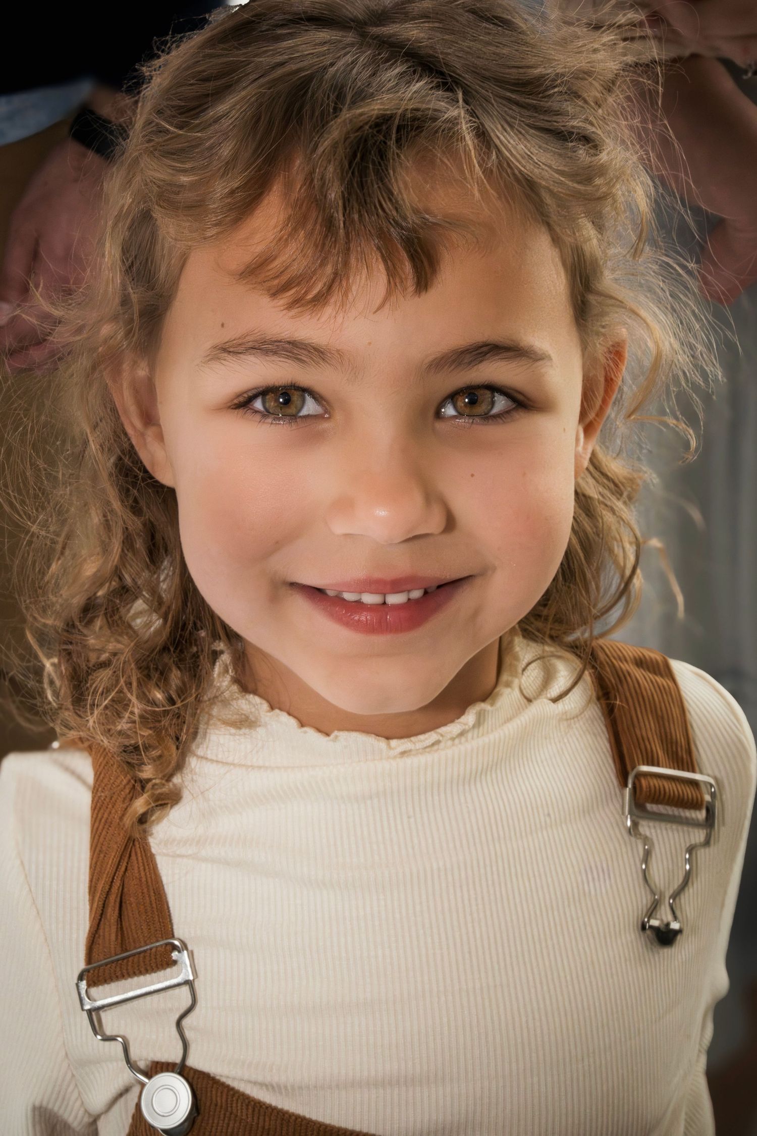 A series of close-up portrait shots showing a child wearing a cream-colored sweater and brown overalls.
