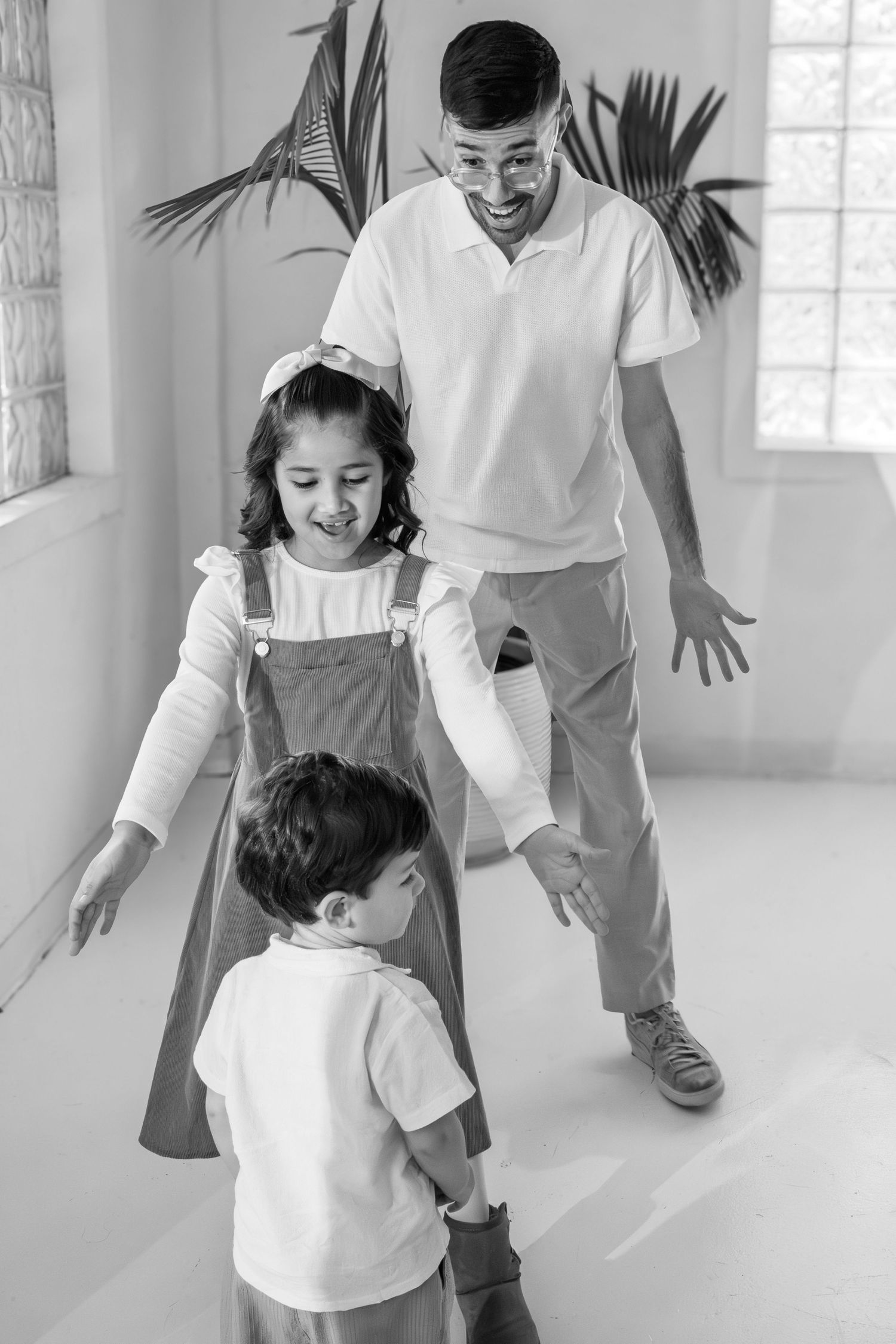 Family wearing white outfits plays and laughs together in a bright indoor setting.