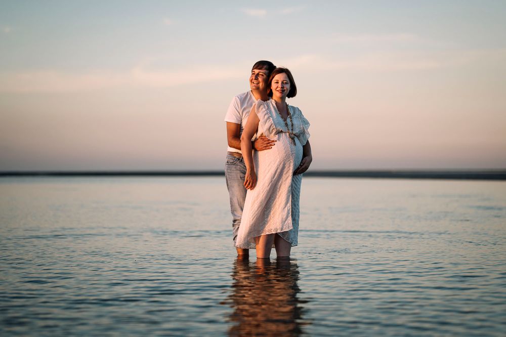 Servizio fotografico maternity nell'acqua bassa del mare al tramonto, in Puglia.
