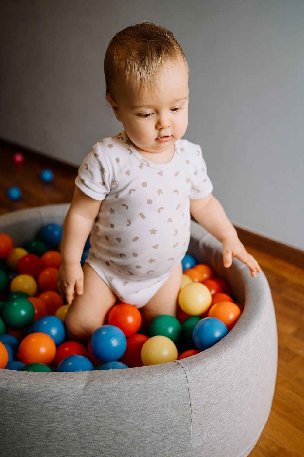 Bambino piccolo che gioca in una piscina piena di palline colorate.